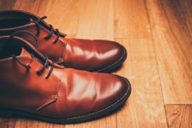 Brown leather shoes on a wooden floor to show bata is not an indian brand